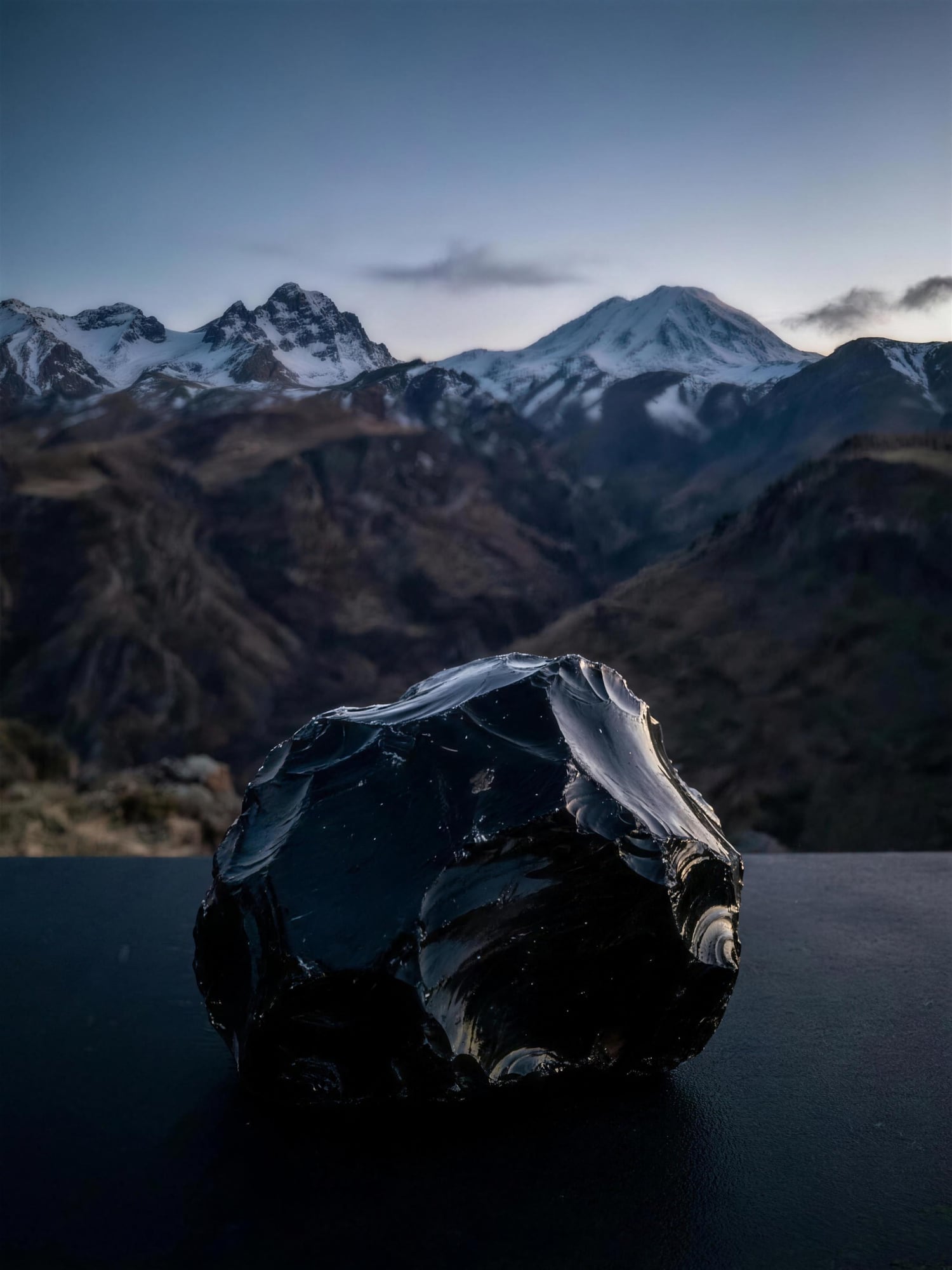 A raw block of obsidian before the Armenian mountains at dusk